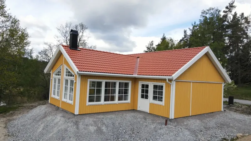 Nybyggt gult trähus med tegeltak — fritidshus byggt av Premie Bygg i Örebro